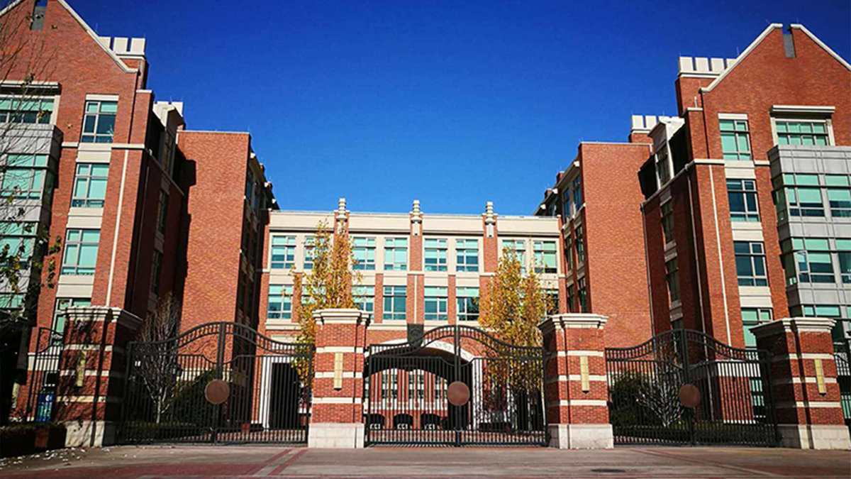     Beijing Keystone Academy campus featuring red brick buildings with ornate entrance gates and clear sky.