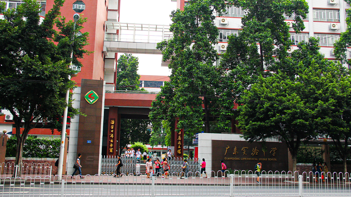 Guangdong Experimental Middle School entrance with students gathering near gates and school signage.