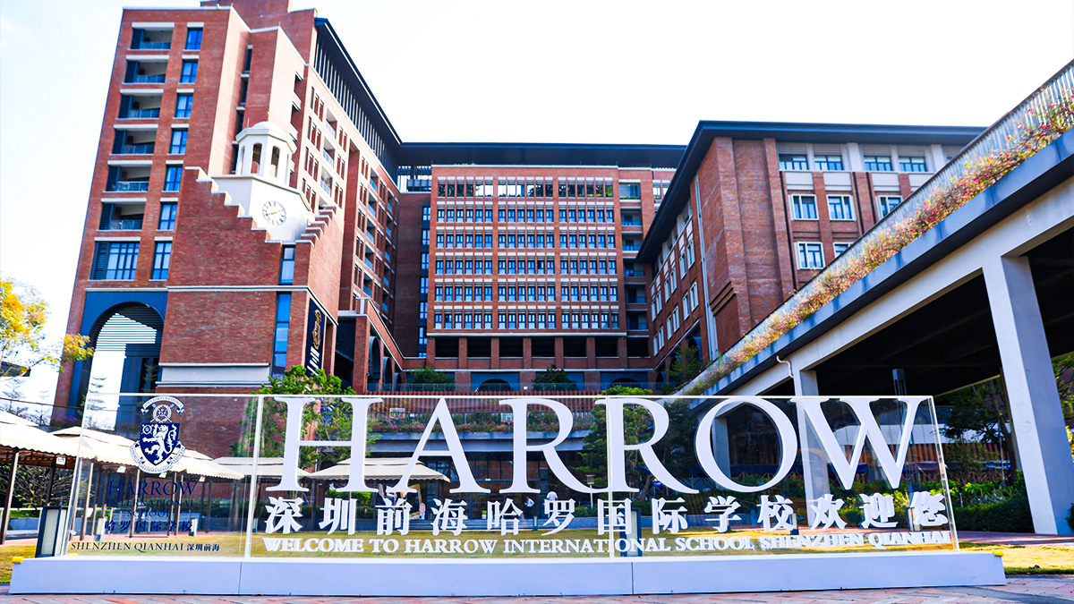 Harrow International School campus entrance featuring modern brick buildings and prominent school signage.