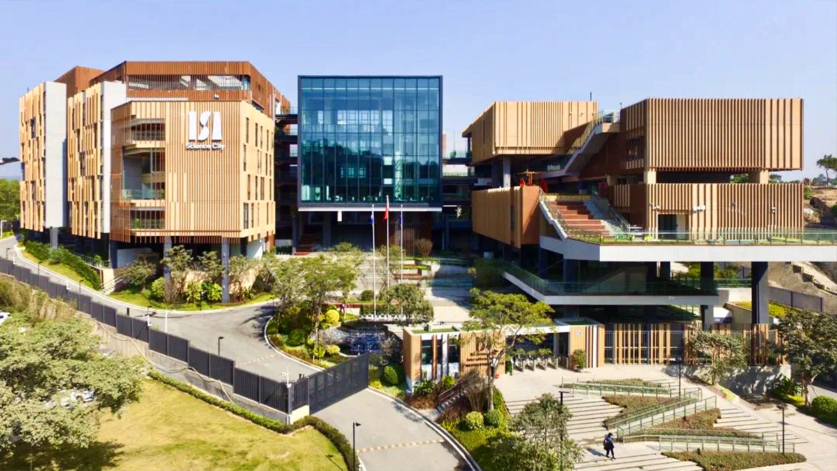 Modern educational building with glass center, trees, and flags at main entrance.