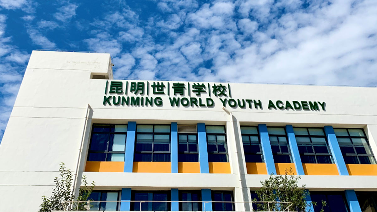 Front facade of Kunming World Youth Academy with large windows and bilingual identification signage.