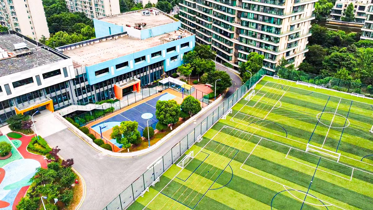 Aerial view of the British School of Nanjing campus with sports fields and buildings.