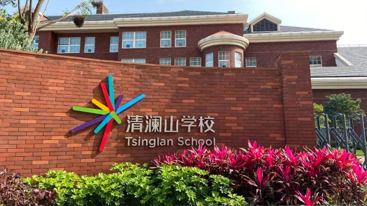 Tsinglan School entrance wall with colorful logo and red brick buildings behind