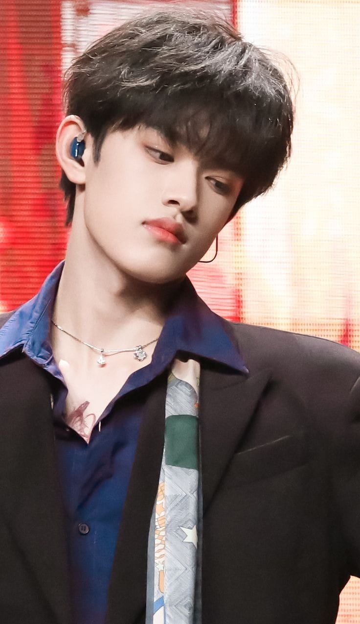 Zhang Ji–inspired stage portrait, youthful performer in dark blazer with in-ear monitor